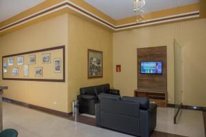 een woonkamer met banken en een flatscreen-tv bij Hotel Iguaçu Centro in Foz do Iguaçu