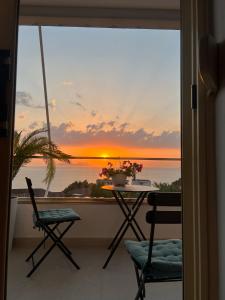 d'un balcon avec une table et des chaises et un coucher de soleil. dans l'établissement Sunny breeze apartment, à Vlorë