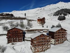 a group of buildings in the snow next to a mountain at Les Menuires : Duplex 4 Pièces 8/10 pers, Wifi, Casier à Skis - FR-1-452-83 in Les Menuires