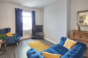 a living room with a blue couch and a tv at Pretty house in the North Yorkshire Moors in Boosbeck