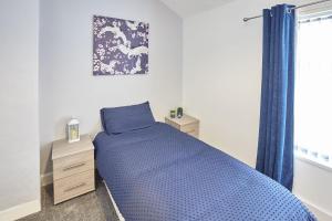 a bedroom with a blue bed and a window at Pretty house in the North Yorkshire Moors in Boosbeck