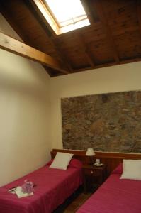 a bedroom with two beds and a stone wall at Casa rural Las Palmeras in Vallehermoso