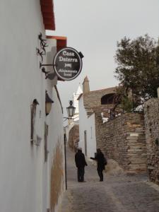 dos personas caminando por un callejón con un cartel en un edificio en Casa Daterra en Monsaraz