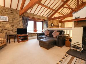 a living room with a leather couch and a tv at Haworth Barn in Stainforth
