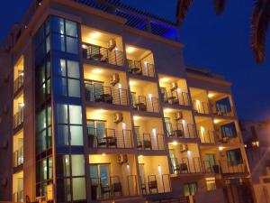 a tall building with windows and balconies at night at Apartments and Rooms Grand Palazzo in Budva