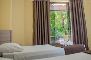 een slaapkamer met 2 bedden en een raam bij Hotel Iguaçu Centro in Foz do Iguaçu