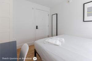 a white bedroom with a bed and a white chair at West Broadway Quarters by Thatch in Boston