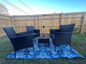 three chairs and a table in a yard with a fence at Simplicity Stays NOLA in New Orleans