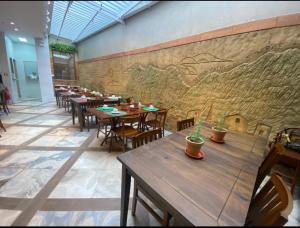 塞拉塔利亞達的住宿－EMA HOTEL，一间带木桌和椅子的餐厅以及壁画