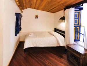 een slaapkamer met een bed en een houten vloer bij Hotel Museo la Posada del Molino in El Cocuy