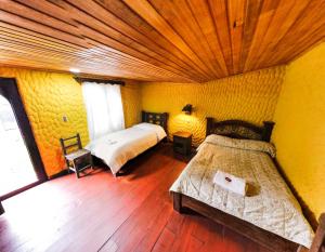 1 dormitorio con 2 camas y suelo de madera en Hotel Museo la Posada del Molino en El Cocuy