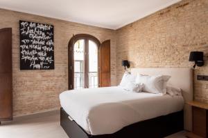 a bedroom with a large white bed and a brick wall at Casa ART Sevilla in Seville