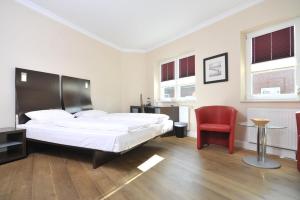 a bedroom with a large bed and a red chair at Hotel Kiose in Wenningstedt