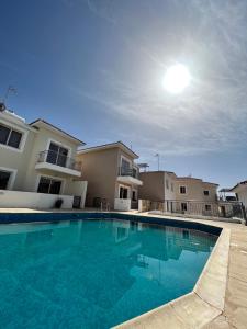 a large blue swimming pool in front of a house at Coral View in Peyia