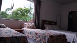 um quarto de hotel com duas camas e uma janela em Refúgio Ouro Fino Kitnets Casas e Apartamentos em Paraty