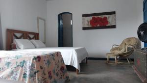 1 dormitorio con 2 camas, 1 silla y 1 pintura en Refúgio Ouro Fino Kitnets Casas e Apartamentos, en Paraty