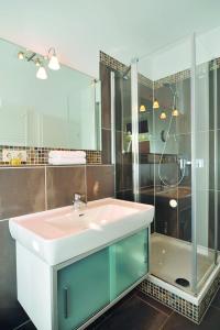 ein Bad mit einem Waschbecken und einer Dusche in der Unterkunft Hotel Kiose in Wenningstedt-Braderup