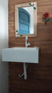 w łazience znajduje się umywalka z lustrem na drewnianej ścianie w obiekcie Refúgio Ouro Fino Kitnets Casas e Apartamentos w mieście Paraty