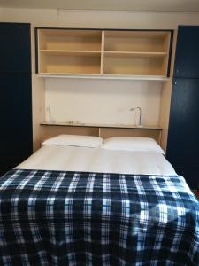una cama con una manta de cuadros azul y blanco en Falco Bianco, en San Daniele del Friuli
