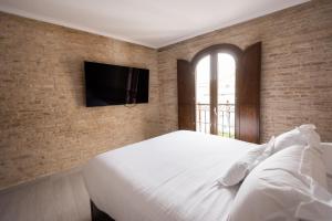 a bedroom with a bed and a tv on a brick wall at Casa ART Sevilla in Seville