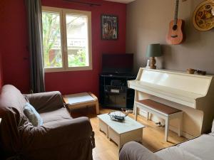 a living room with a couch and a piano at La Maison des Palombes in Francheville