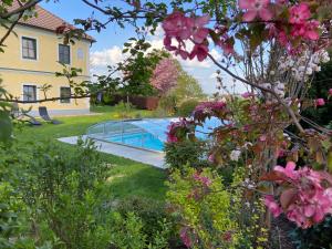 a swimming pool in a yard with pink flowers at Familienbauernhof Strassbauer in Steinakirchen am Forst
