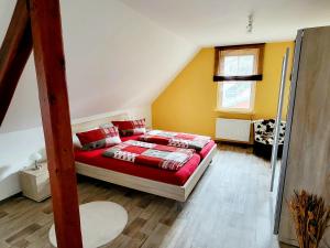 um quarto com uma cama com lençóis vermelhos e uma janela em Ferienhaus Alt Bahnhaus em Ruschberg