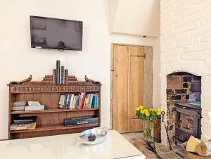 a living room with a tv and a fireplace at Truffle Cottage, Chichester in Chichester