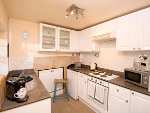 a kitchen with white cabinets and a counter top at Gate Cottage in Matlock