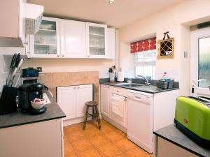 a kitchen with white cabinets and a green appliance at Jewel Cottage in Matlock