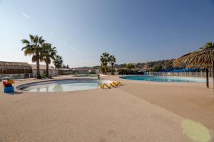 - une piscine bordée de palmiers et un complexe dans l'établissement Mobil home Queen Margaret, à Fréjus