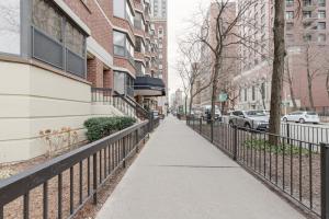 a sidewalk next to a fence next to a building at Gold Coast 2BR w Gym Pool nr Oak St Beach CHI-207 in Chicago