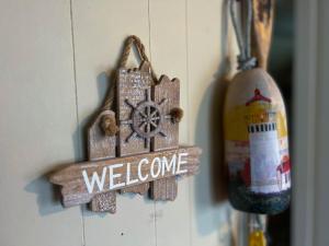a wooden welcome sign hanging on a wall at Enchanted Cottages by the Sea in Seaview
