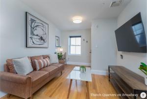 a living room with a couch and a flat screen tv at West Broadway Quarters by Thatch in Boston