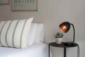 una lámpara en una mesa junto a una cama con almohadas blancas en Acogedor Studio Pleno Barrio de Recoleta 2C en Buenos Aires