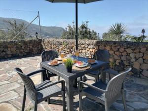 a table with chairs and an umbrella on a patio at LA TAGORA Conect with the nature & relax in Icod de los Vinos