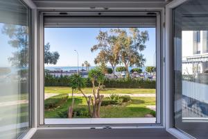 uma janela com vista para uma palmeira em Sea View with Parking by LU&CIA em Málaga