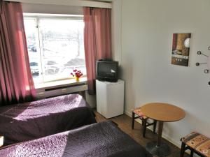 Habitación pequeña con cama, TV y mesa. en B&B Retro - Guesthouse Kupittaa, en Turku
