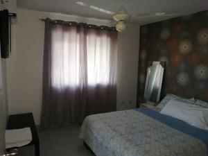 a bedroom with a bed and a window with a curtain at Sweet Alar in La Estrella