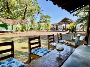 Hotel Tranquilo في لاس بينيتاس: طاولة خشبية مع كراسي وكأس للنبيذ
