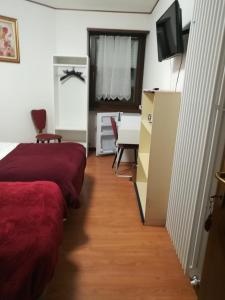 a room with two beds and a table and a television at Falco Bianco in San Daniele del Friuli
