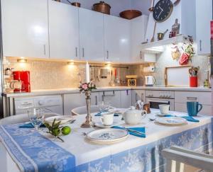 una cocina con armarios blancos y una mesa con platos en Stone suite in the center of Corinth en Kórinthos