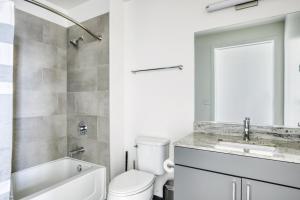 une salle de bain avec toilettes, lavabo et miroir dans l'établissement Logan Sq 2BR w Roof Gym 1 block to L CHI-480, à Chicago 28 autres photos