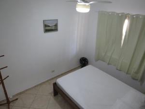 a small white room with a bed and a window at Casa na Rua da Praia com TV e Wi-fi in Pontal do Paraná