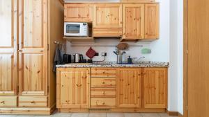 una cucina con armadi in legno e forno a microonde di Appartamento Santa Caterina a Santa Caterina Valfurva
