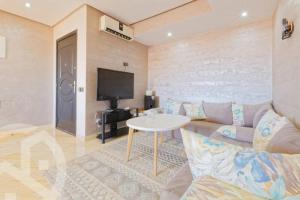 - un salon avec un canapé et une télévision dans l'établissement Chez ASSYL: résidence avec 3 piscines, à Marrakech
