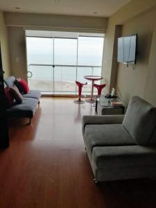 sala de estar con sofás, mesa y ventana grande en Beachfront Condo San Miguel, en Lima