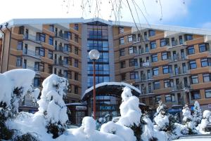 a building with snow covered trees in front of it at PM Services Flora Apartments in Borovets
