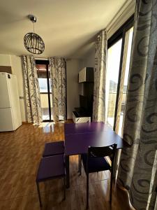 ein Raum mit einem lila Tisch und Stühlen und einem großen Fenster in der Unterkunft Apartamento Vacacional Gara in Adeje