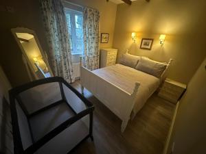 a small bedroom with a white bed and a chair at Doon Cottage Sleeps 8 Hottub Gym Area Pool Table in Tempo